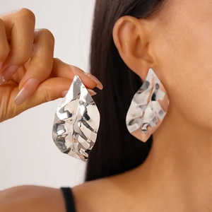 Chic silver leaf earrings with textured hammered finish on elegant female model