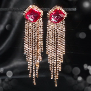 Macro shot of long red crystal tassel earrings with sparkling rhinestones and gold plating