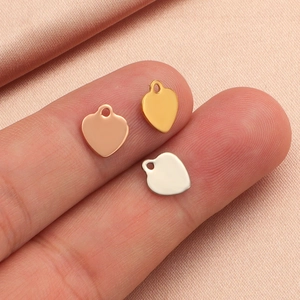 Polished heart pendants in gold, silver, and rose gold finishes on pink silk background