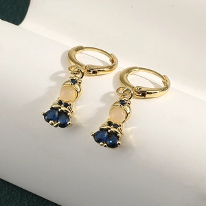 Detail view of gold drop earrings with pear-cut blue gemstone and white round stones