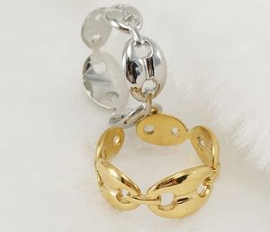 Vista plana de anillos de grano de café en oro y plata sobre fondo de felpa