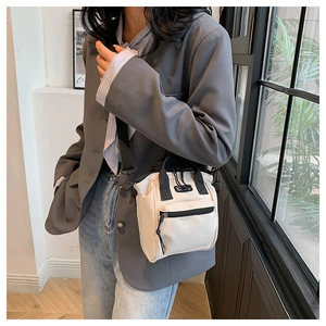 Détail du sac bandoulière blanc cassé avec poignée noire et poche zippée sur modèle