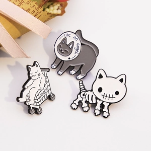 Detail of three cartoon cat enamel pins including a skeleton cat and shopping cart design