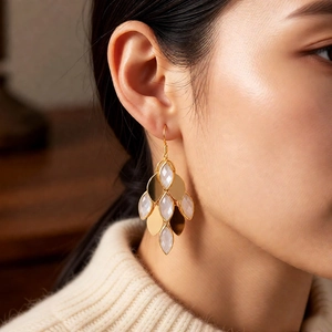 Detailed view of vintage gold-plated drop earrings with white stones on a model