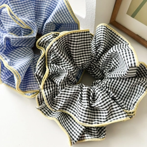 Detail showing oversized plaid scrunchies in blue and black with yellow wavy edges