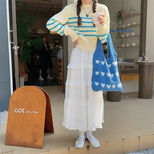 Detailed knit texture of a blue heart jacquard handbag on a yellow striped sweater