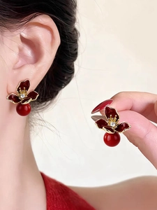 Close-up of vintage flower drop earrings with red pearls and sparkling crystals