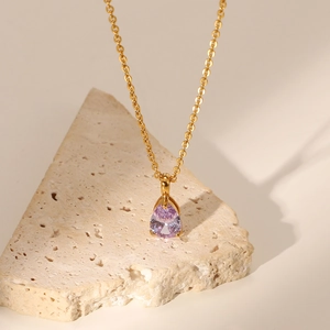 Macro detail of 18K gold plated chain necklace with a vibrant pink zircon stone pendant