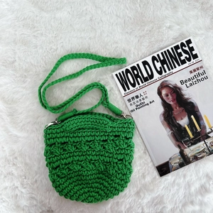 Detail of green handmade crochet round crossbody bag with textured woven pattern and strap