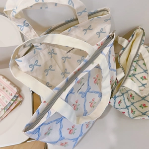 Close-up of floral canvas tote bags with blue bow patterns and zipper closure detail