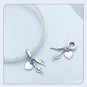 Détail macro de breloques en argent S925 avec motifs de cœur, note de musique et ailes