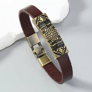 Detail of brown leather bracelet featuring a bronze metal buckle with floral engraving
