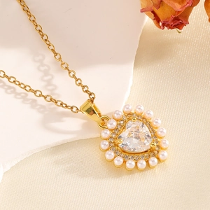 Macro di una collana a cuore dorata con cristallo centrale e bordo di perle bianche