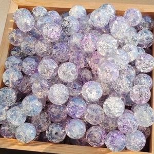 Macro shot of purple cracked-glass round beads for jewelry making in a wooden box