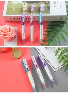 Close-up of three glowing unicorn pens with colorful grips on a pink and grey background
