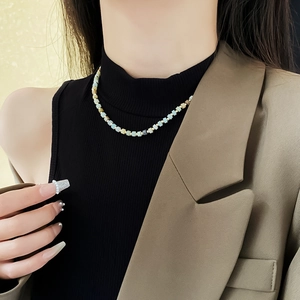 Detail of colorful beaded necklace with blue and cream pearls on a model neck