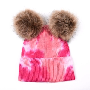 Détail du bonnet en tricot tie-dye rose avec deux pompons marrons en fausse fourrure