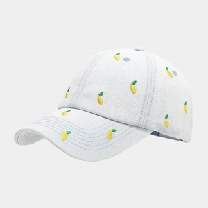 Close-up of small lemon embroidery on a light blue denim baseball cap with twill texture