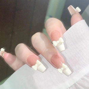 Detailansicht eleganter French-Tip-Aufklebenägel mit weißen 3D-Schleifen-Akzenten.