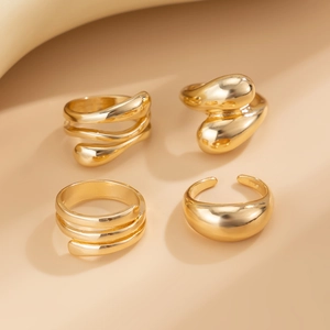 Detail of four-piece gold irregular bangle bracelet set with smooth minimalist finishes