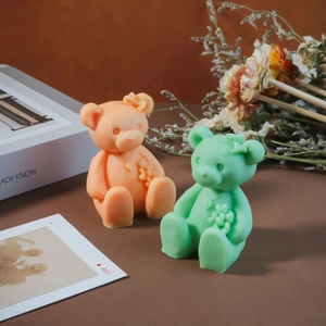 Close-up of cute orange and mint green cartoon bear candles with flower details