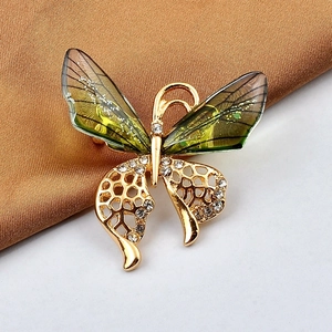 Detailed close-up of a butterfly brooch with green gradient wings and crystal accents