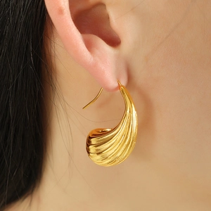 Orecchini a cerchio geometrici cavi placcati in oro 18K con texture su modella donna