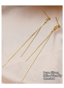 Macro shot of long gold tassel silver earrings on pink silk, skin-friendly material