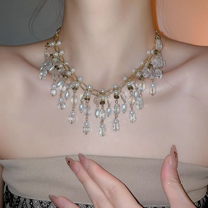 Detail of luxurious gold layered necklace with crystal tassels and white pearl pendants
