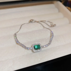 Detailed close-up of emerald cut green stone bracelet with vintage halo design