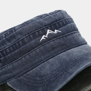 Detail of white mountain embroidery on washed navy cotton canvas cadet cap texture