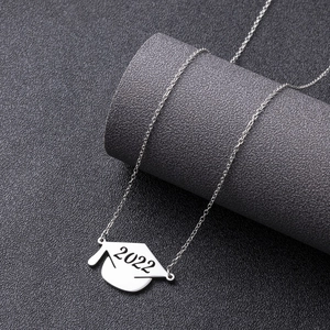 Detailed view of silver graduation cap pendant with 2022 engraving on jewelry stand