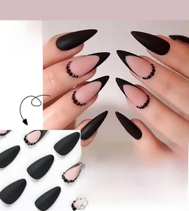 Macro detail of matte pink and black French stiletto press-on nails with small rhinestones