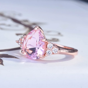 Macro side view of rose gold pear cut pink diamond ring with sparkling side stones