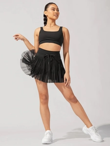 Detail of black pleated mesh skirt with layered design and high waist for active women
