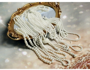 Close-up of layered baroque pearl necklaces with crystal spacers on a vintage mirror