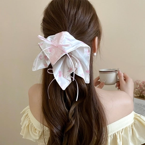 Détail de l'élastique à fleurs avec dentelle rose et nœud sur les cheveux du modèle