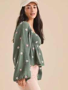 Détail de la broderie florale rose sur les manches bouffantes de la blouse verte