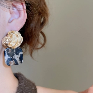 Close-up of vintage square shell earrings with blue leopard print and gold metal studs