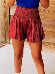 Detail of red metallic high waisted loose athletic shorts with shiny fabric texture