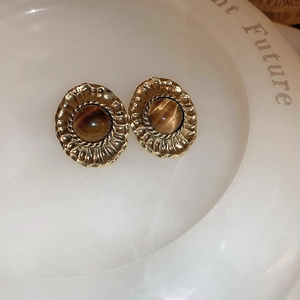 Macro shot of vintage tiger eye stone earrings with gold geometric wrinkled borders