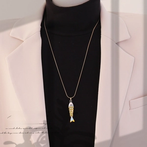 Detailed view of long gold koi fish pendant necklace with blue and yellow enamel inlay