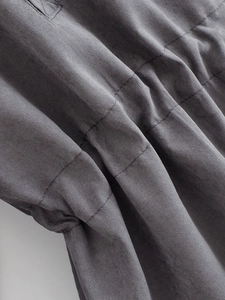 Detailed close-up of dark grey fabric texture with parallel stitching on a women's windbreaker