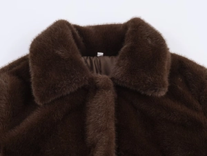 Detailed close-up of dark brown faux fur coat featuring thick texture and lapel design