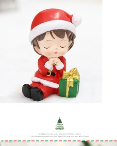 Close-up of a resin Christmas girl figurine in red outfit holding a green gift box