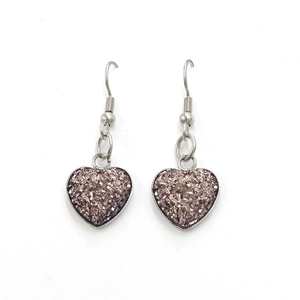 Detailed macro view of heart-shaped earrings featuring bronze glitter crystals and silver hooks