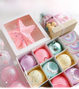 Detail of pink star tree topper and macaron Christmas balls in partitioned white box