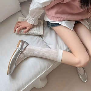 Detail von silbernen Mary-Jane-Schuhen kombiniert mit weißen Spitzen-Ballettsocken