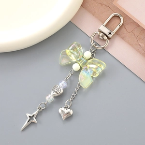 Iridescent bow keychain with silver star and heart charms on a pink-grey background