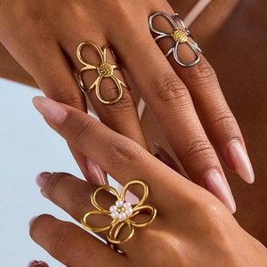 Titanium steel flower rings with pearls shown on hand in gold and silver finishes